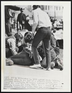 Kent State Univer. students come to the aid of a wounded youth. Ohio National Guardsmen, on campus because of disturbances the past few days, fired into a crowd of students Monday, Reportedly killing four and wounding 13. Protesters burned ROTC Building