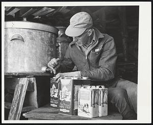 Milton Fullerton - So. Woodstock, Vt., filling warm maple syrup into gallon & half gallon cans - for sale.