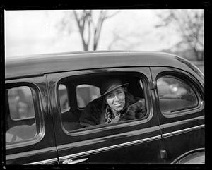 A woman smiling from the back seat of a vehicle