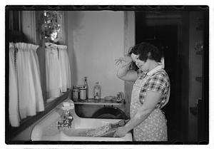 A woman doing laundry at a sink with a washboard