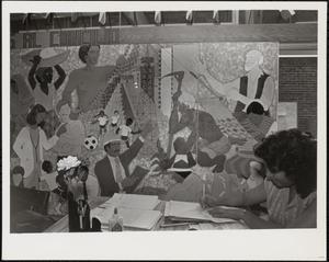 Woman working at a desk by a wall mural