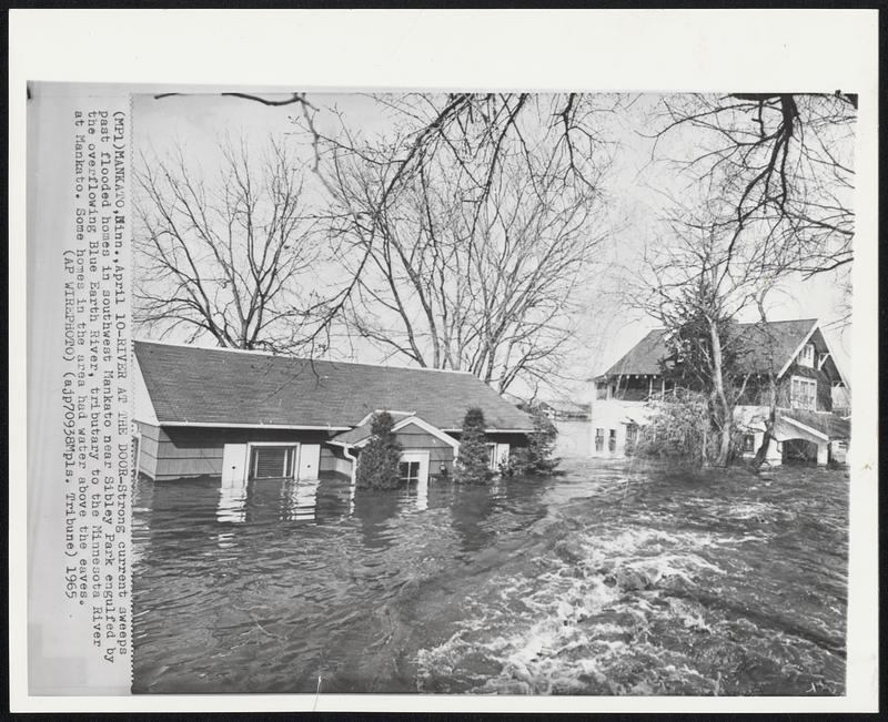 River at the Door-Strong current sweeps past flooded homes in southwest Mankato near Sibley Park engulfed by the overflowing Blue Earth River, tributary to the Minnesota River at Mankato. Some homes in the area had water above the eaves.