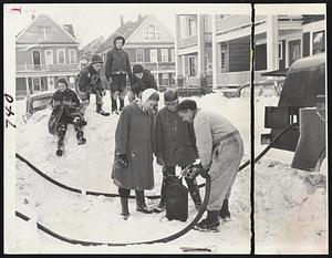 Kerosene Pumping Station on Hallam street, Uphams Corner, Dorchester, found Joan Wegand, Robert Gallagher and Thomas J. Donahue, left to right, pumping oil. This was one of the emergency pumping stations set up by Mayor Collins when trucks could not navigate clogged streets.