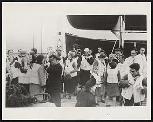 One of the Lifeboat Drills During Atlantic Crossing of Manhattan Aboard the S.S. Manhattan which arrived here today after an uneventful crossing from Europe, Tourist Class Chief Steward Raymond Feuerstake shows passengers how to adjust their life preservers, at one of the emergency lifeboat drills which were staged during the Atlantic crossing. No submarines were sighted during the voyage and the Manhattan escaped the sever Atlantic storm that struck the liner President Harding of the same line last Tuesday.