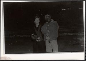 A young man and woman posing outside