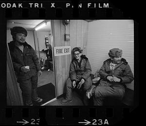 Three men in fur hats by fire exit, North Slope camp, Anchorage, Alaska