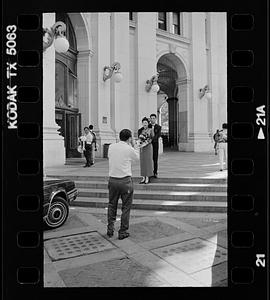 Formally dressed couple being photographed, possibly after a civil wedding