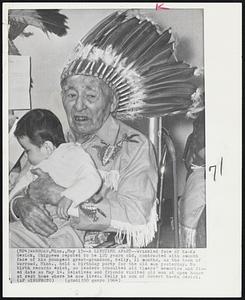 A Lifetime Apart -- Wrinkled face of Ka-Ka Gesick, Chippewa reputed to be 120 years old, contrasted with smooth face of his youngest great-grandson, Kelly, 11 months, as the town of Warroad, Minn., held a birthday party for the old man yesterday. No birth records exist, so leaders consulted old timers' memories and fixed date as May 14. Relatives and friends visited old man at open house at rest home where he now lives. Kelly is son of Robert Ka-Ka Gesick.