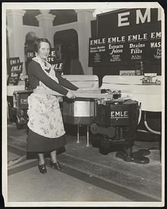 All-around Housemaid. "Emle" a robot maid that acts as cook, masseur and dish washer, made its appearance at the annual radio and electrical show in Chicago Jan. 19, called the electro-mechanical labor eliminator, this current-directed and tireless worker will vibrate excess weight of its owner, press dresses, chops meat, ream fruit, barbeque meat and perform several other culinary duties. When the day's work is done, the apparatus folds up and retires under the kitchen sink. Peggy Bryon of Chicago is shown demonstrating "Emle's" weight reducing abilities.