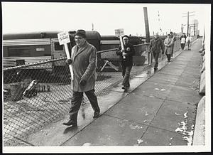Railroad union pickets walk past idle core at Dover St yards.