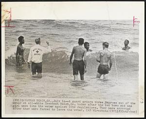 A guard orders three Negroes out of the water at all-white Savannah Beach, Ga. today after the two boys and one girl went into the water against city regulations. They were arrested after they were forced to leave the water.