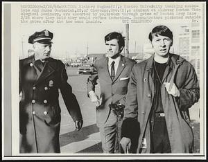 Richard Hughes (C), a Boston University teaching associate and James Oesterich, 22, of Cheyenne, Wyo. (R), a student at Andover Newton Theological Seminary, are escorted by policeman through gates of Boston Army Base 2/26 where they said they would refuse induction. Demonstrators picketed outside the gates after the two went inside.