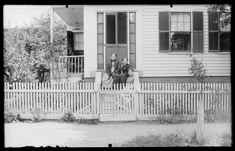 Unknown house with 3 women on steps, picket fence