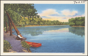 A man fishing by the side of a lake, a boat in the water beside him