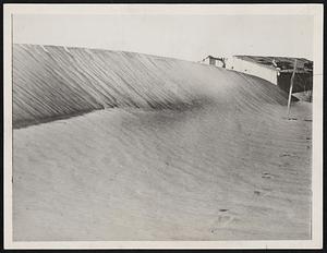 The swirling dust clouds have piled sand up against the farmer's fence, so that it may no longer be seen, but has all the appearance of a sand dune.