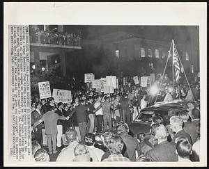 Loyal Response to Demonstration--An auto bearing a large American flag drives slowly by demonstrators at the University of California campus in Berkeley as they began lining up for their march down Telegraph Avenue last night to the Oakland city limits. A sign on the side of the car said "We love our country!" The marchers were protesting U.S. involvement in Vietnam.
