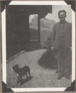 An unidentified man stands with a Boston terrier in front of him