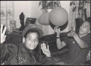 Two boys hanging out and one spinning a basketball on his finger