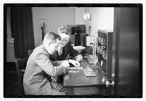 A boy sitting next to a man using an unidentified device