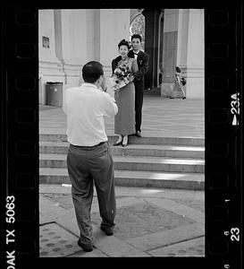 Formally dressed couple being photographed, possibly after a civil wedding