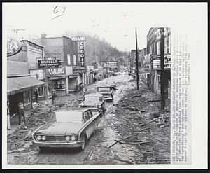 Harlan, Ky. -- Big Cleanup Begins In Eastern Kentucky -- Autos drive along path cleared of debris in downtown Harlan after flood waters of Cumberland River subsided from record crest of 29 feet late yesterday. The fast-rising flood brought debris from the Kentucky hills which caused damage in the millions of dollars.