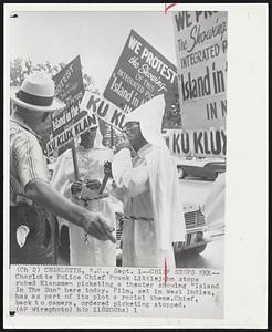 Chiefs Stops KKK--Charlotte Police Chief Frank Littlejohn stops robed Klansmen picketing a theater showing "Island In The Sun" here today. Film, set in West Indies, has as part of its plot a racial theme. Chief, back to camera, ordered picketing stopped.