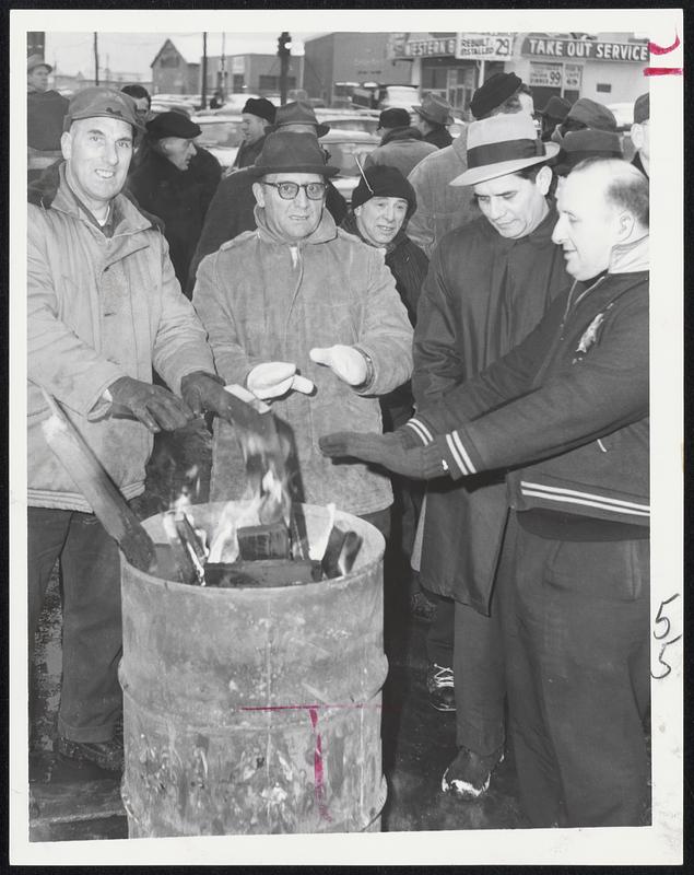 Chilly strikers warm hands at fire as they picket Lynn General Electric plant today.