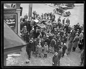 A group of people standing by a car that hit a lamppost