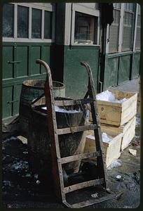 Dolly, barrels, and crates by exterior wall