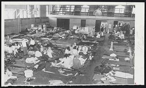 Evacuation Center -- Cots fill the gymnasium at the Abraham Lincoln High School, Council Bluffs, Iowa, yesterday, furnishing a haven for Council Bluffs residents evacuated from the low-lying section of the city threatened by the rising waters of the Missouri river. Women and children while away the time as their menfolk man the levees and aid in other volunteer work in the flood-threatened city.