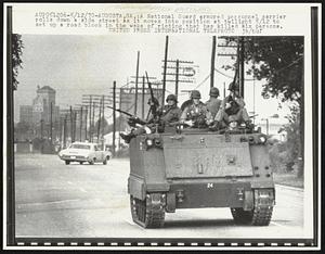 A National Guard armored personnel carrier rolls down a side street as it moves into position at twilight 5/12 to set up a road block in the wake of rioting that has killed six persons.