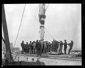 A group of men working on the rigging of a sailing ship