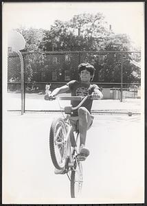Boy doing bike tricks on basketball court