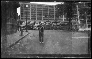 A man stands, cars in the background