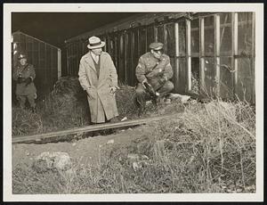 Daniel A. Gray, of the internal revenue staff with Corp. Henry W. Ellison, of the Foxboro barracks examining the four-inch pipe line which left the plant of the still, and extended 1 1/2 miles through fields and under main roads to a well in which the mash was deposited.