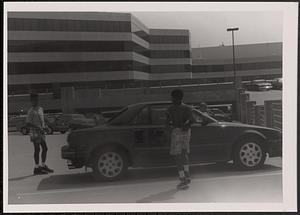 Three children standing around a car in a parking lot