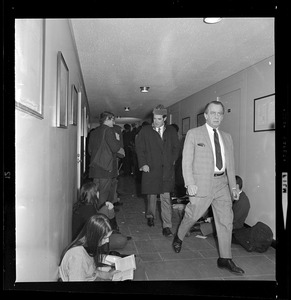 President Morris Abrams, in hat, walking down hallway during Brandeis University administration building sit-in