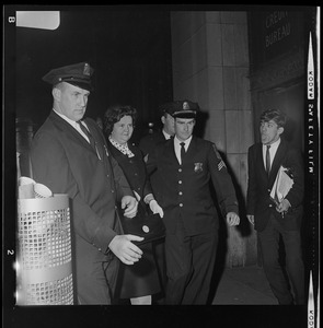 Louise Day Hicks escorted by Sgt. John Hames and unidentified police officers through protest against school segregation outside Boston School Committee meeting