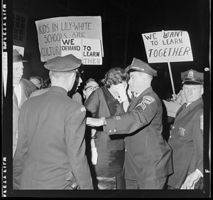 Louise Day Hicks escorted by Sgt. John Hames and unidentified police officers through protest against school segregation outside Boston School Committee meeting