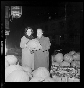 Louise Day Hicks with unidentified man holding pumpkin at fruit stand