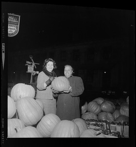 Louise Day Hicks with unidentified man holding pumpkin at fruit stand