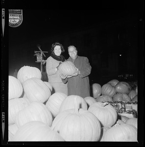 Louise Day Hicks with unidentified man holding pumpkin at fruit stand