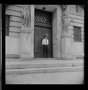 Police officer standing outside entrance to unidentified school