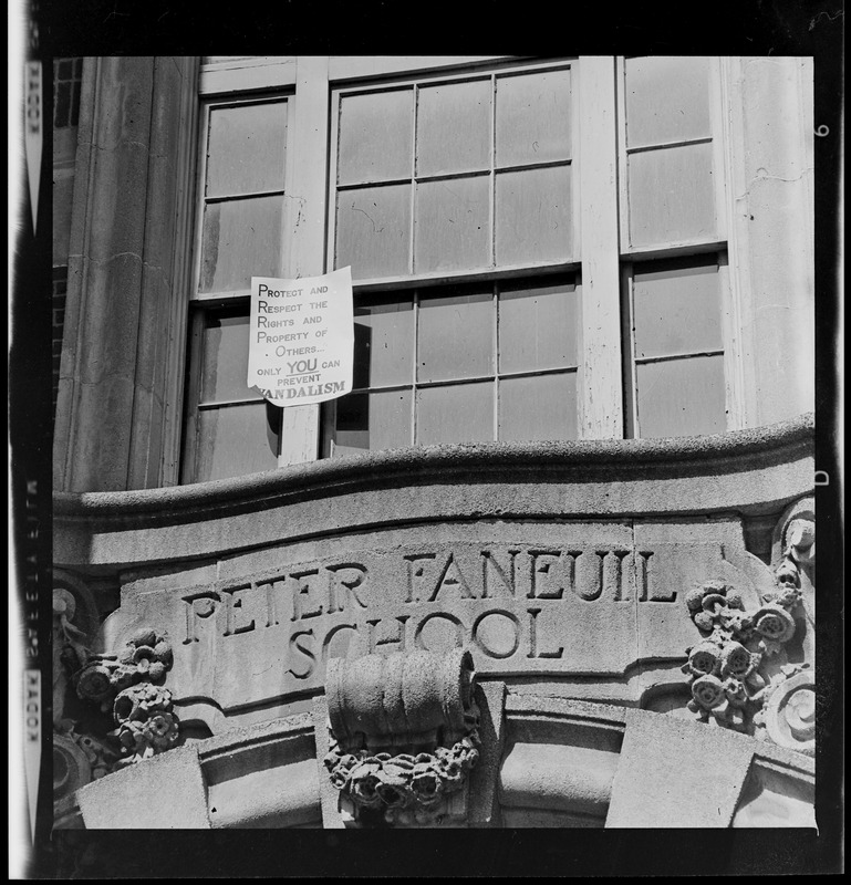 Sign about preventing vandalism above entrance of Peter Faneuil School