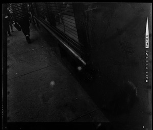 People walking on sidewalk past window with blinds