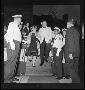 Unidentified man and woman in formalwear descending stairs at opening of Music Hall Theatre