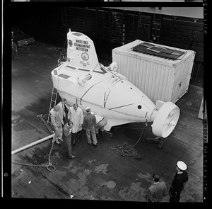 Back from H-bomb search is miniature sub Alvin as it is unloaded in Boston for trip to Woods Hole. Crew members watching are George Roderson, Marvin McCamis, Valentine Wilson, William Rainnie, Jr.