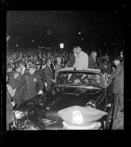 President Johnson and Lt. Gov. Bellotti, surrounded by Secret Service men, wave to crowds as they ride in motorcade from Logan Airport