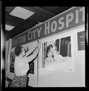 Woman setting up a Boston City Hospital exhibit for the opening of the War Memorial Auditorium