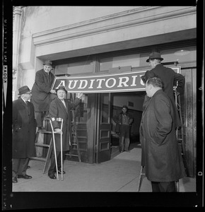 Mayor John Collins poses with men hanging "Auditorium" sign over doorway at War Memorial Auditorium
